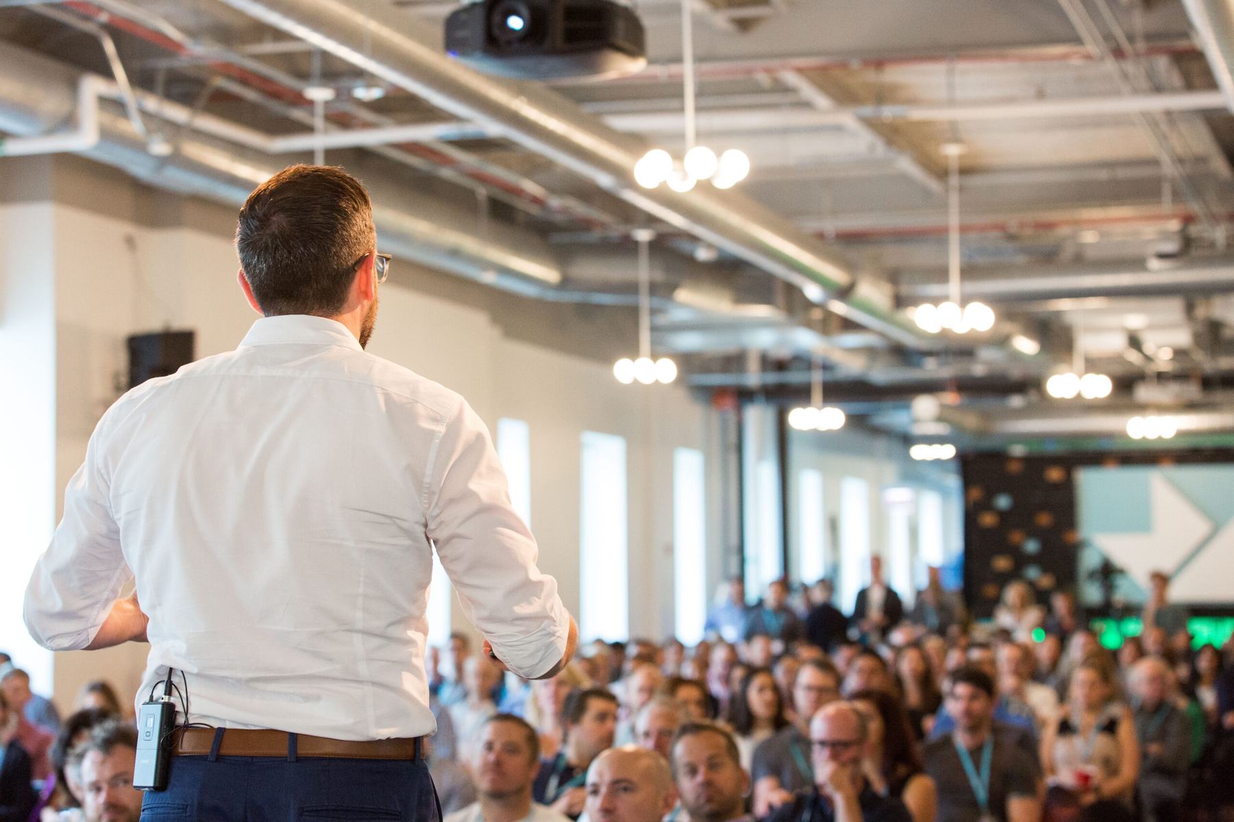 Joe Martin on stage, facing a full room